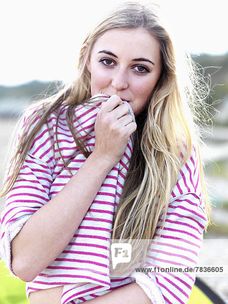 A young woman covering her mouth with her shirt and smiling playfully
