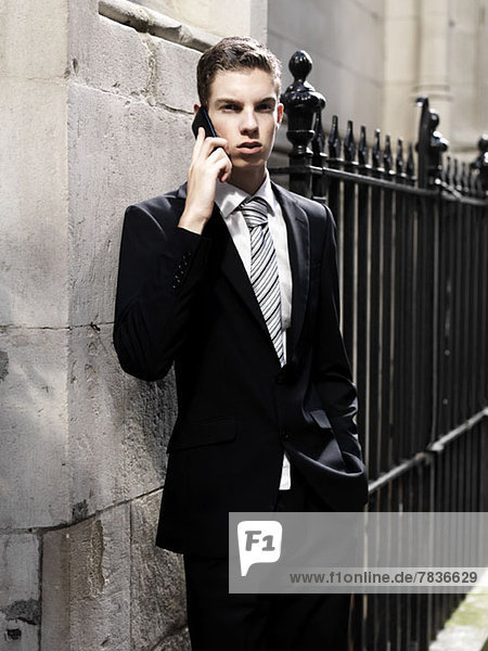Ein junger Geschäftsmann  der ernsthaft aussieht  während er sein Smartphone hört.
