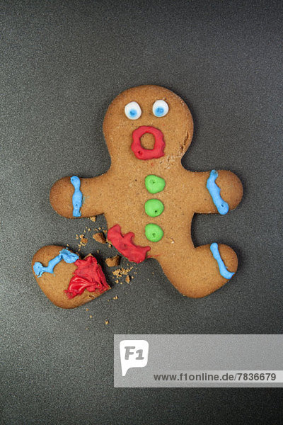 A gingerbread man looking shocked with a broken leg