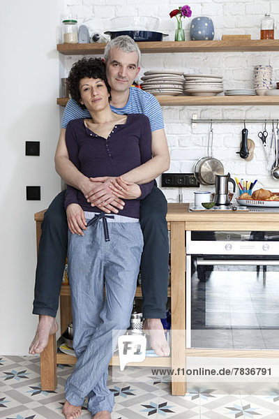 Ein liebevoll lächelndes  altersgemischtes Paar in der Küche
