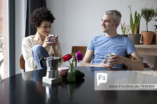 A cheerful hip mixed age couple enjoying breakfast together in their dining room