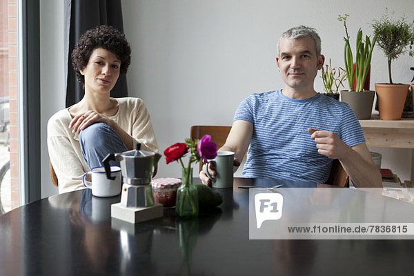 A hip mixed age couple having breakfast in their modern dining table