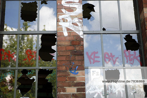 Detail eines Gebäudes mit kaputten Fenstern und Graffiti