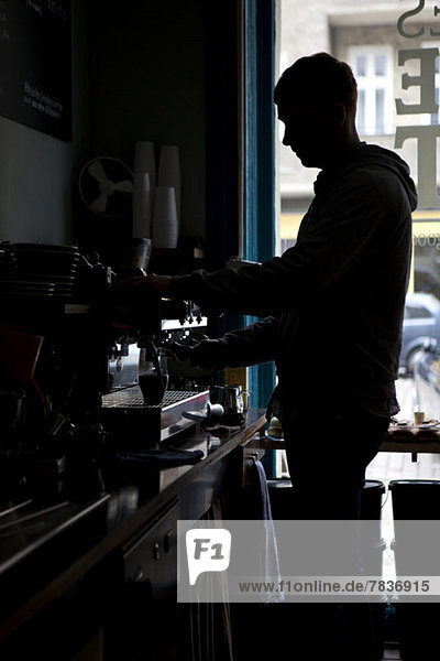 A barista making espresso at an espresso maker in a coffee shop