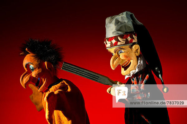 Punsch aus dem klassischen Puppenspiel Punch and Judy bedroht den Teufel mit einer Waffe
