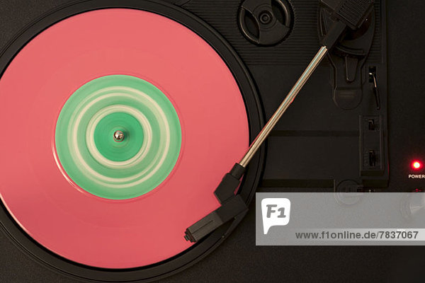 Eine rosa und grüne Schallplatte  die auf einem Plattenspieler spielt.