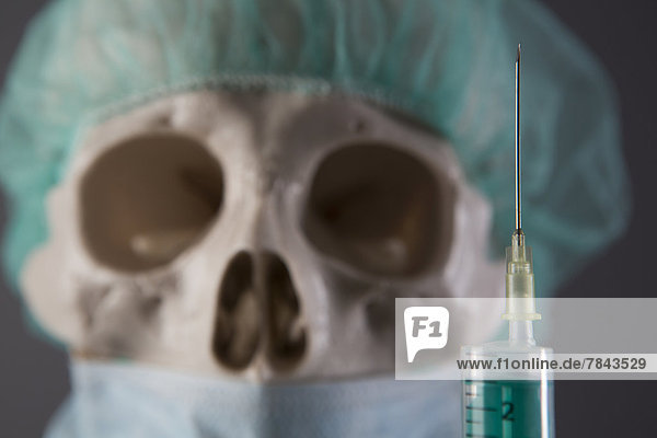 Skeleton dressed as a doctor with cap  surgical mask and syringe