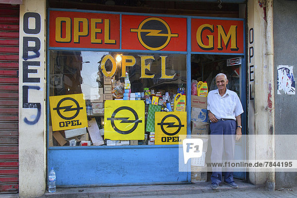 Alter Mann steht an einem Geschäft  Opel Ersatzteilhandel
