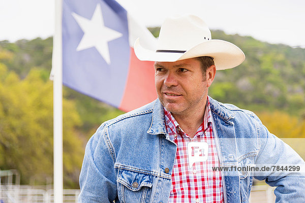 Texas  Mature man standing in front of flag with cowboy hat