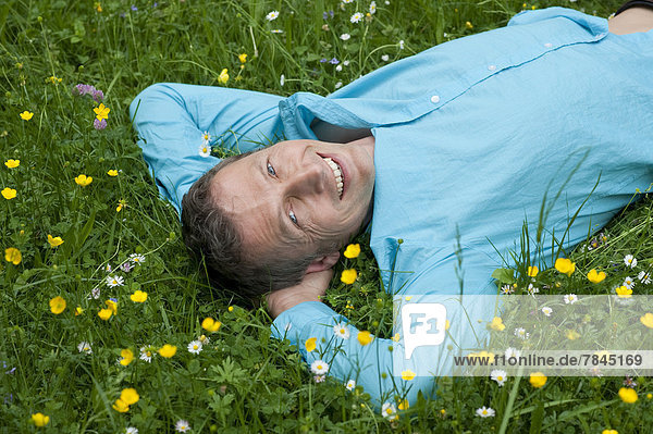 Porträt eines reifen Mannes  der sich im Garten entspannt  lächelnd