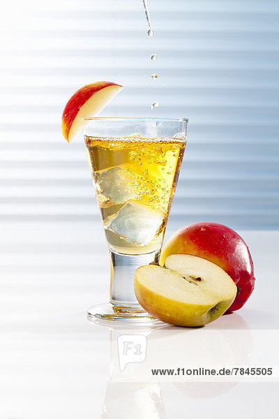 Glas mit Apfelsaft und halbierten Äpfeln