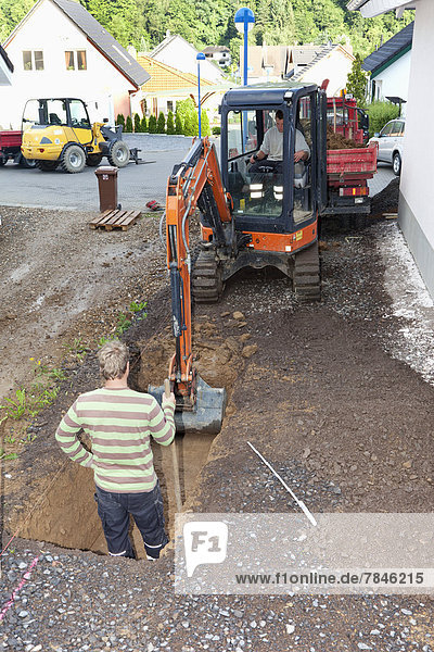 Europe  Germany  Rhineland Palatinate  Men working with excavator during house building