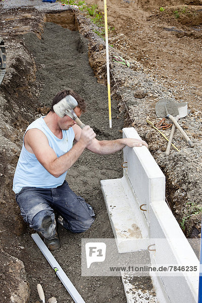 Europe  Germany  Rhineland Palatinate  Man installing corner stone in soil while house building