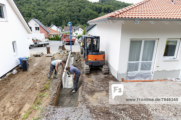 Europe  Germany  Rhineland Palatinate  Men installing corner stone in soil while house building