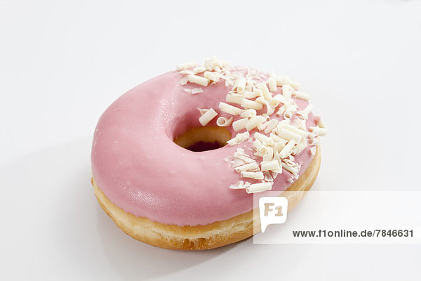 Doughnut topped with pink icing on white background close up