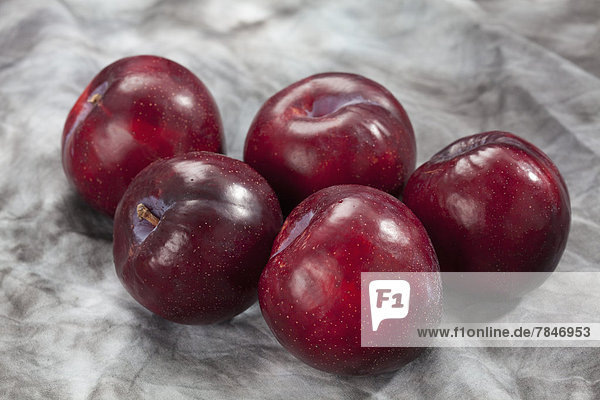 Red plums on grey background  close up