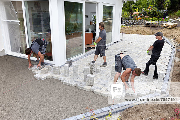 Germany  Rhineland Palatinate  Young men assembling paving stones