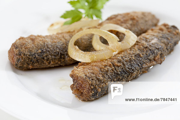 Gebratener Hering mit Zwiebeln und Essig auf dem Teller Nahaufnahme