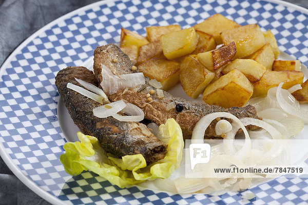 Fried herring with roasted potatoes and onions on a plate