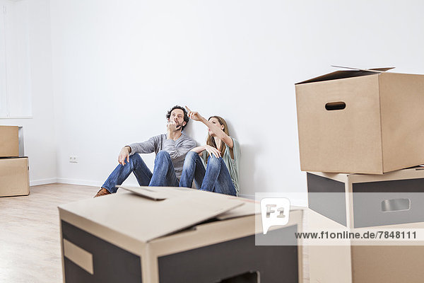 Couple sitting on floor with moving boxes