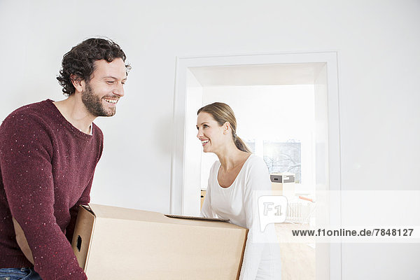 Couple unloading boxes in their new house  smiling