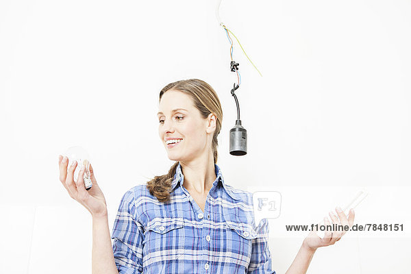 Woman holding electric bulb  smiling