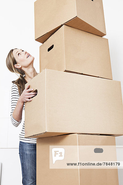 Woman carrying stack of cardboard boxes  looking up