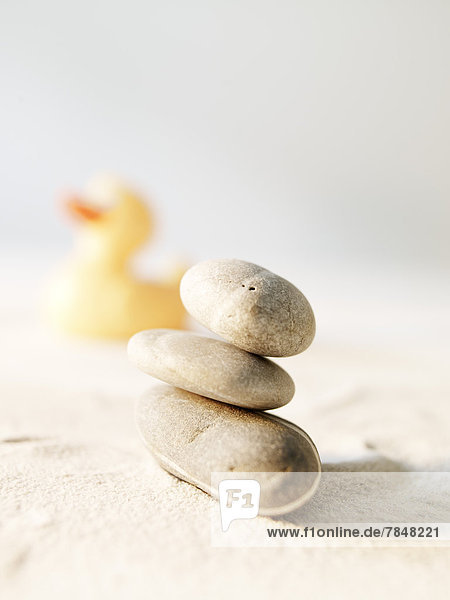 Stack stones and rubber duck on sand