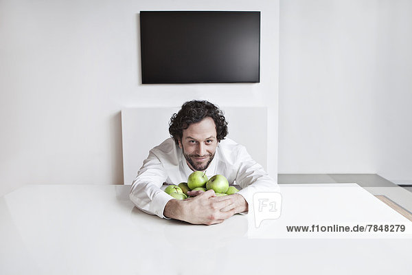 Deutschland  Nordrhein-Westfalen  Köln  Portrait eines Geschäftsmannes mit Äpfeln  lächelnd