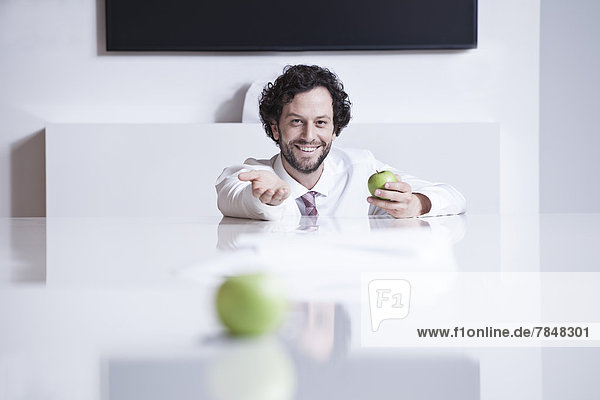 Deutschland  Nordrhein-Westfalen  Köln  Portrait eines Geschäftsmannes mit grünem Apfel  lächelnd