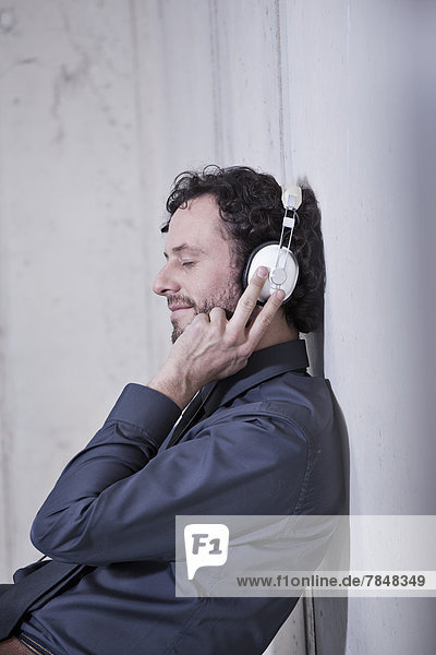 Deutschland  Nordrhein-Westfalen  Köln  Geschäftsmann beim Musikhören mit Kopfhörern