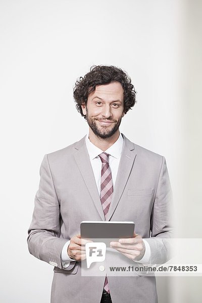 Deutschland  Nordrhein-Westfalen  Köln  Portrait eines Geschäftsmannes mit digitalem Tablett  lächelnd