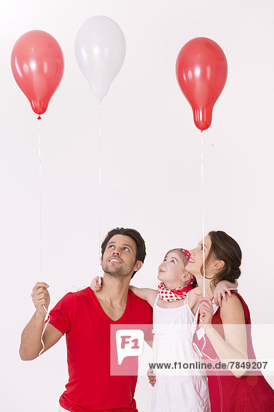 Familie hält Luftballons  lächelnd
