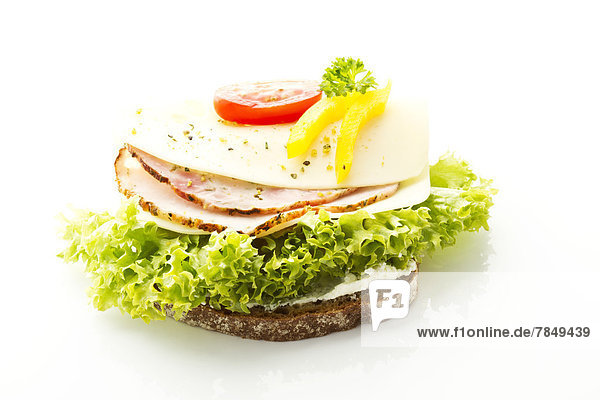 Fitness-Sandwich mit Frischkäse  Schinken  Tomaten und Gurken auf weißem Grund  Nahaufnahme