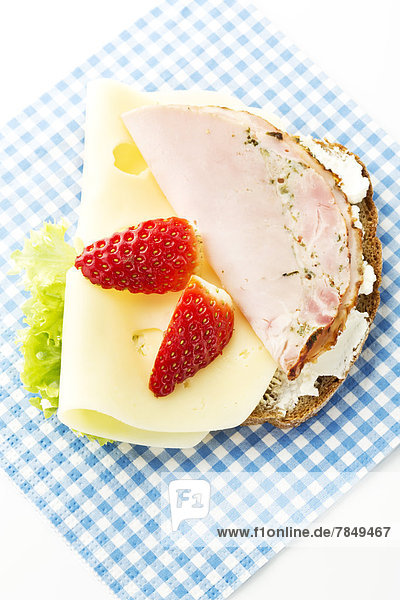 Fitness-Sandwich mit Frischkäse  Käse und Schinken-Erdbeer-Scheibe auf weißem Grund  Nahaufnahme