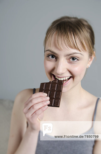 Portrait of young woman eating chocolate  smiling