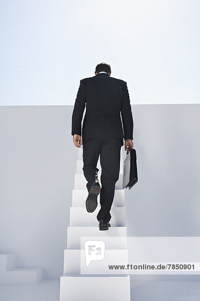 Geschäftsmann im schwarzen Anzug beim Treppensteigen