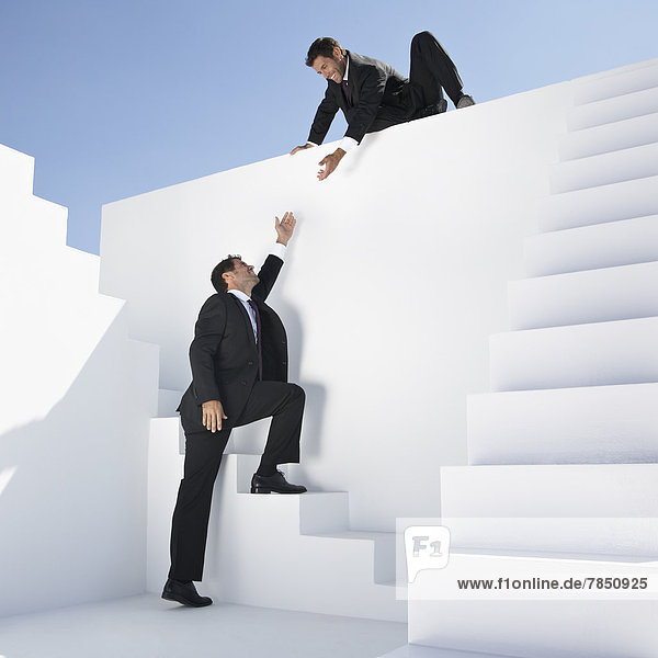 Geschäftsmann hilft einem anderen Mann beim Treppensteigen