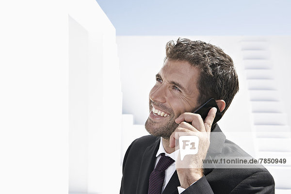 Businessman in black suit talking on mobile phone  smiling