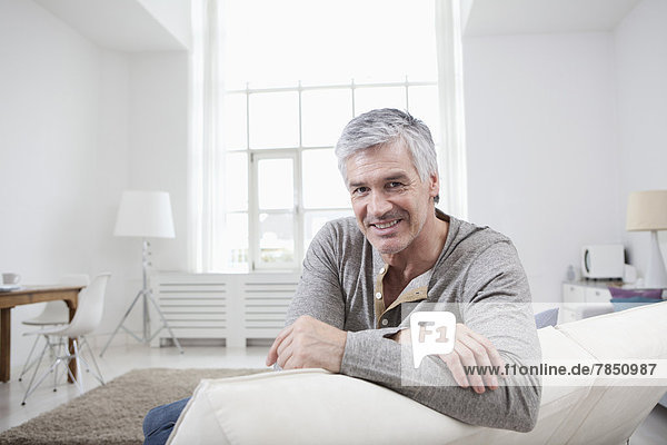 Porträt eines reifen Mannes auf der Couch sitzend  lächelnd