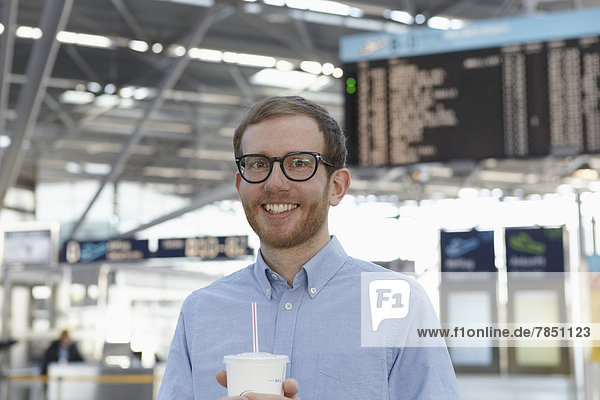 Mittlerer Erwachsener Mann mit Getränk am Flughafen