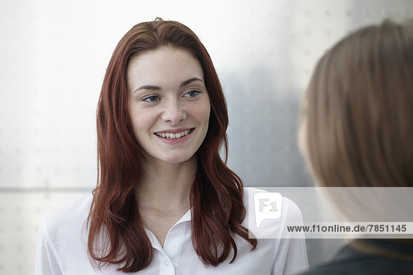 Young woman and teenage girl looking at each other  smiling