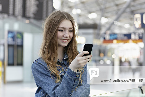 Teenager-Mädchen mit Handy am Flughafen