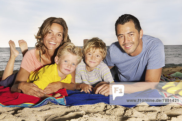 Spain  Portrait of family lying on beach at Palma de Mallorca  smiling
