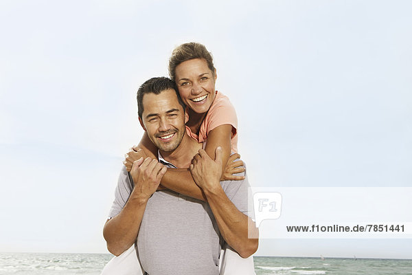 Spain  Mid adult man giving piggy back ride to woman  smiling