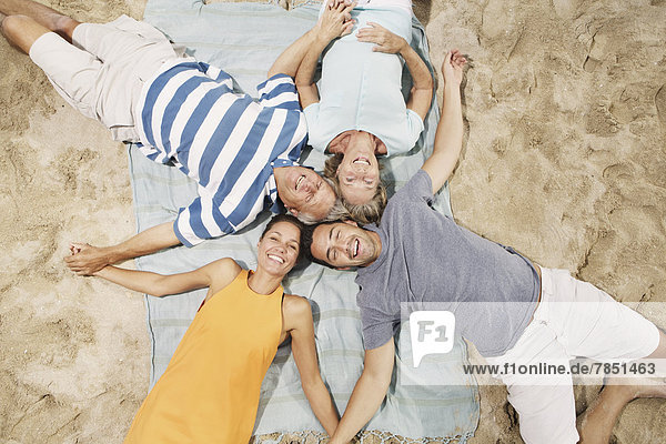 Spanien  Familie am Strand von Palma de Mallorca liegend  lächelnd