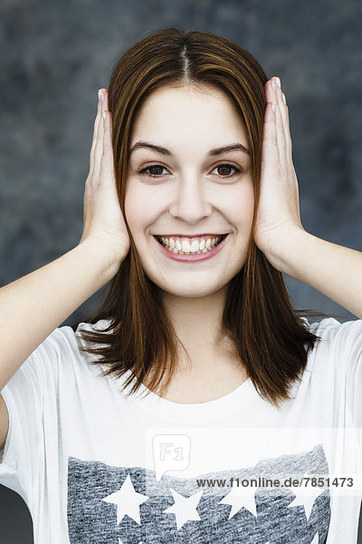 Portrait of young woman covering ears  smiling