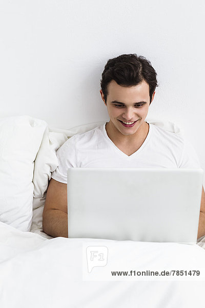 Junger Mann mit Laptop  lächelnd
