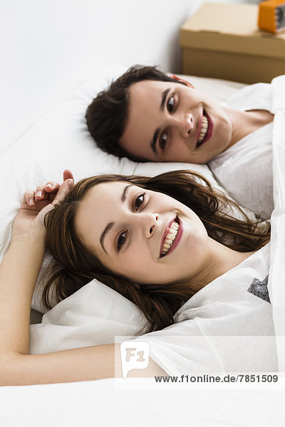 Young couple lying on bed  smiling