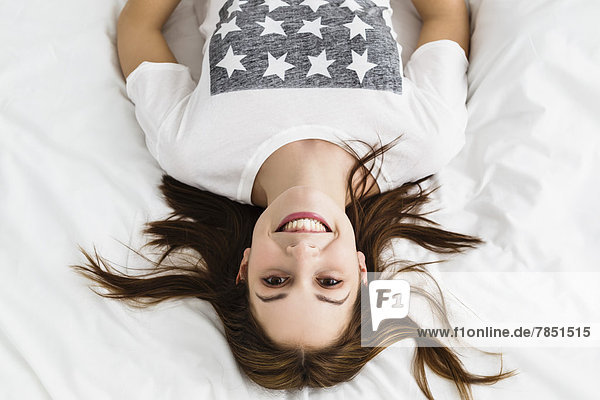 Portrait of young woman lying on bed  smiling